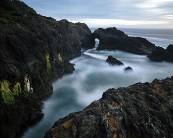 Scenic view of rock formation in sea against sky