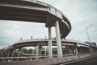 Bridges in city against cloudy sky