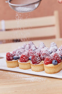 Dressing of french traditional blueberry and raspberry tartlets of sprinkled with powder outside. 