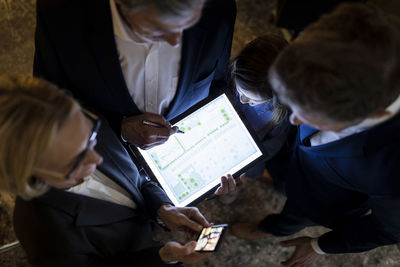 Top view of business people and girl looking at shining construction plan on tablet in office