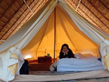 Rear view of woman sitting on bed in the tent 