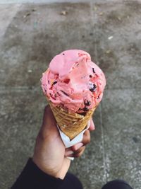 Cropped image of man holding ice cream on road