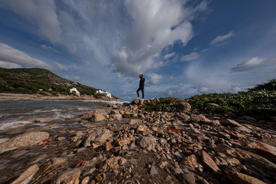 Man standing on rock against sky