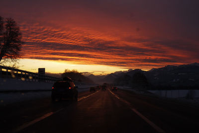 Cars on road against sky during sunset