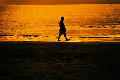 Silhouette man standing at beach during sunset