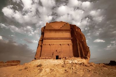 Low angle view of stone structure against cloudy sky