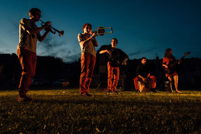 People playing on field against sky at night