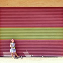 Girl wearing mask against closed shutter during sunny day