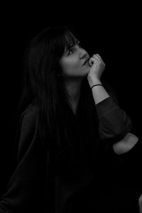 Close-up of girl looking away against black background