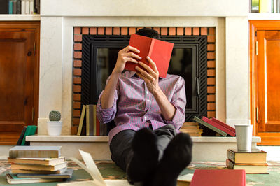 Full length of woman reading book while sitting on table