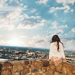 Rear view of woman looking at cityscape against sky