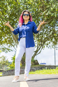 Full length of young woman wearing sunglasses on road in city