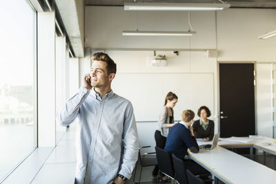 Young man talking on smart phone in classroom