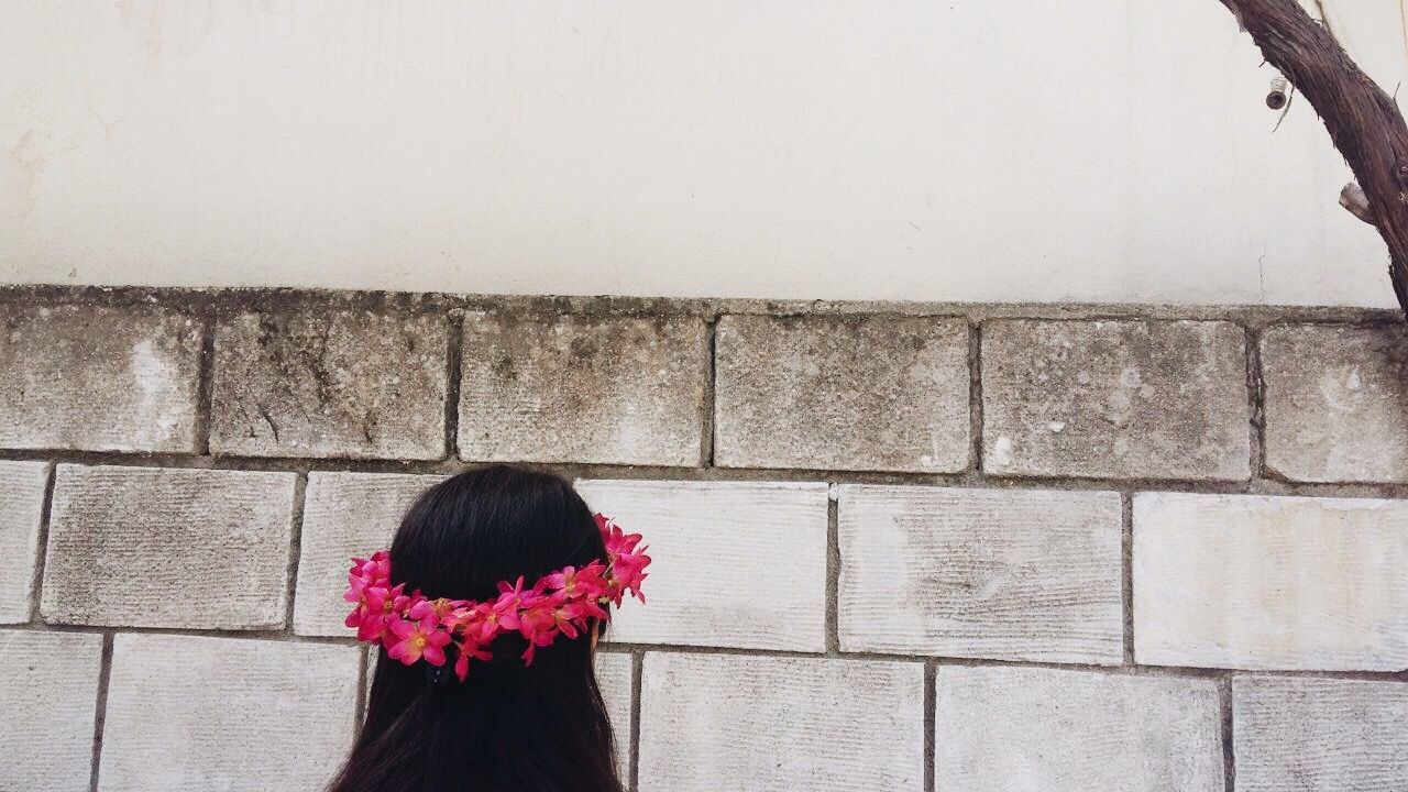 wall - building feature, lifestyles, leisure activity, casual clothing, pink color, rear view, standing, waist up, red, flower, long hair, day, person, in front of, human hair