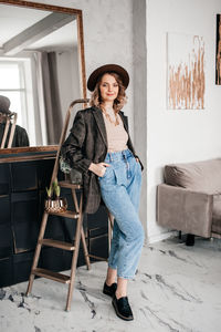 Portrait of young woman standing against wall