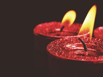 Close-up of burning red candles in darkroom