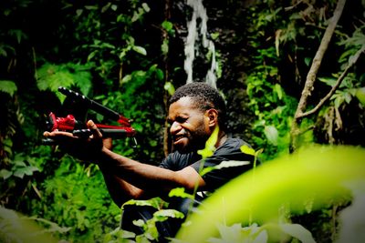 Portrait of man holding plants in forest