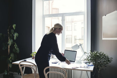 Businesswoman keeping laptop on desk at home office