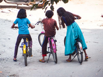 Rear view of friends riding bicycles at beach