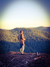 Full length of man with gun standing on mountain against clear sky