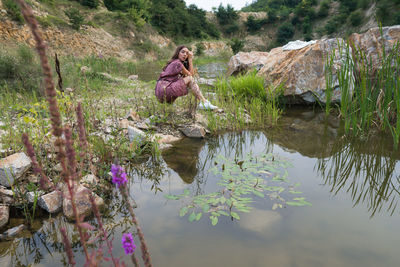 View of beautiful girl siting  by the lake