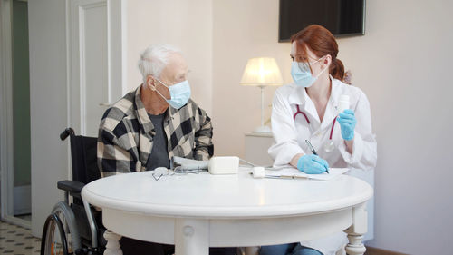 Doctor wearing mask examining patient in clinic