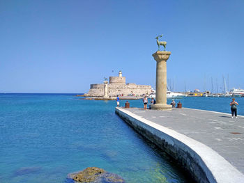 Statue in city against clear blue sky