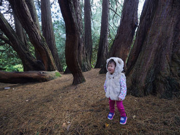 Cute girl standing by trees in forest