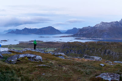 Rear view of man standing by mountains against sky