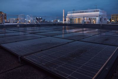 Solar panels by building against sky at dusk