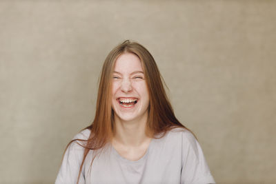 Portrait of young woman standing against wall