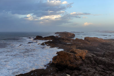 Rock formation on beach against sky