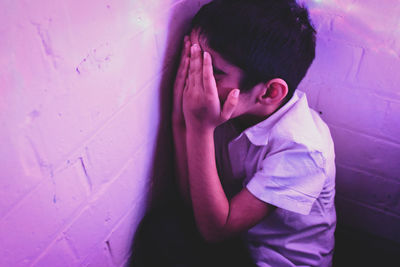 High angle view of boy hiding against pink wall