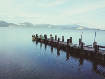 Wooden posts in sea against sky