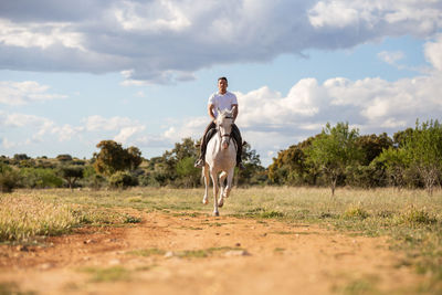 Man riding horse on field against sky