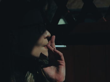 Close-up of woman smoking cigarette in darkroom