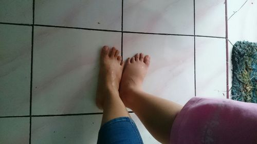 Low section of woman relaxing on tiled floor