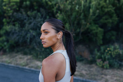Portrait of young woman looking away while standing outdoors