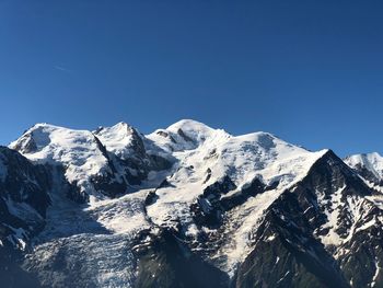 Scenic view of snowcapped mountains against clear blue sky