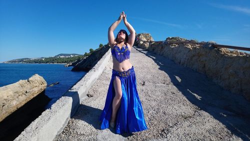 Woman standing by sea against blue sky