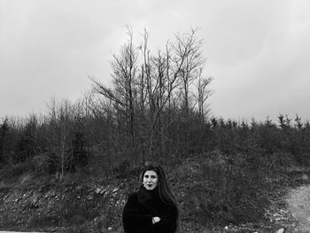 Portrait of young woman standing on field against sky