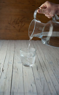 Midsection of person drinking glass on table