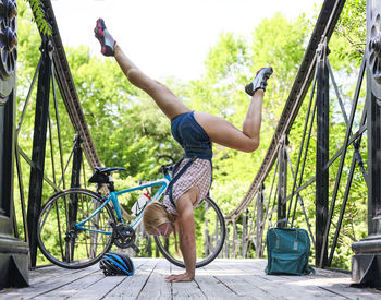 Side view of woman doing handstand on footbridge