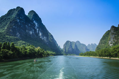 Scenic view of sea and mountains against clear sky