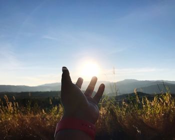 Cropped image of person gesturing on field against sky