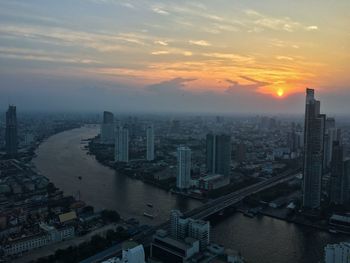 High angle view of chao phraya river amidst cityscape against sky during sunset