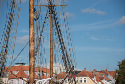 Sailing ship by houses against sky