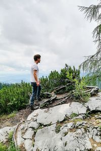Side view of young man standing on rock against sky, berchtesgaden, germany