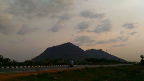 Road by mountains against sky