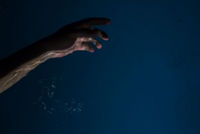 Close-up of hands against clear blue sky